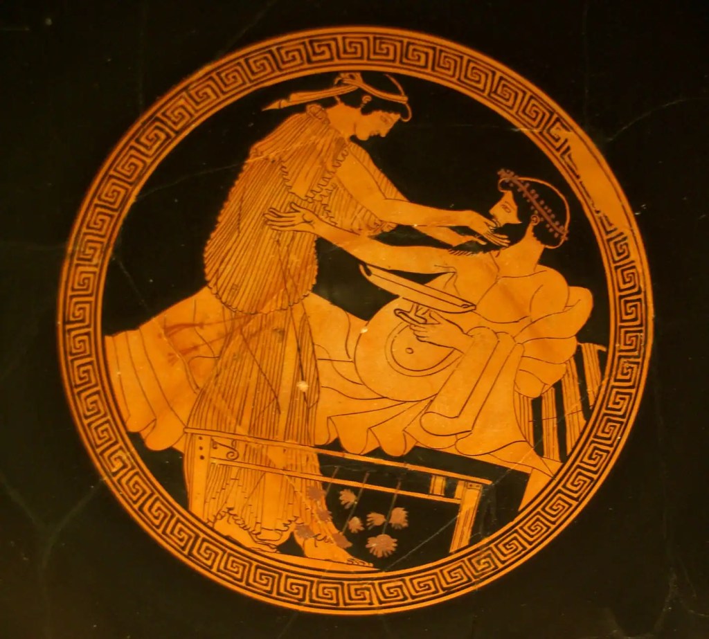 An ancient Greek vase painting depicting a woman in a flowing gown leaning toward a seated man, who is grooming his beard, both appearing in a relaxed setting.