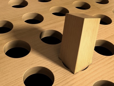 A wooden block placed upright in a board with multiple circular holes.